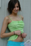 Alyssa strips out of her green and blue outfit by the wall