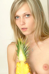Long haired teen blonde posing and playing with toy fruit in the kitchen